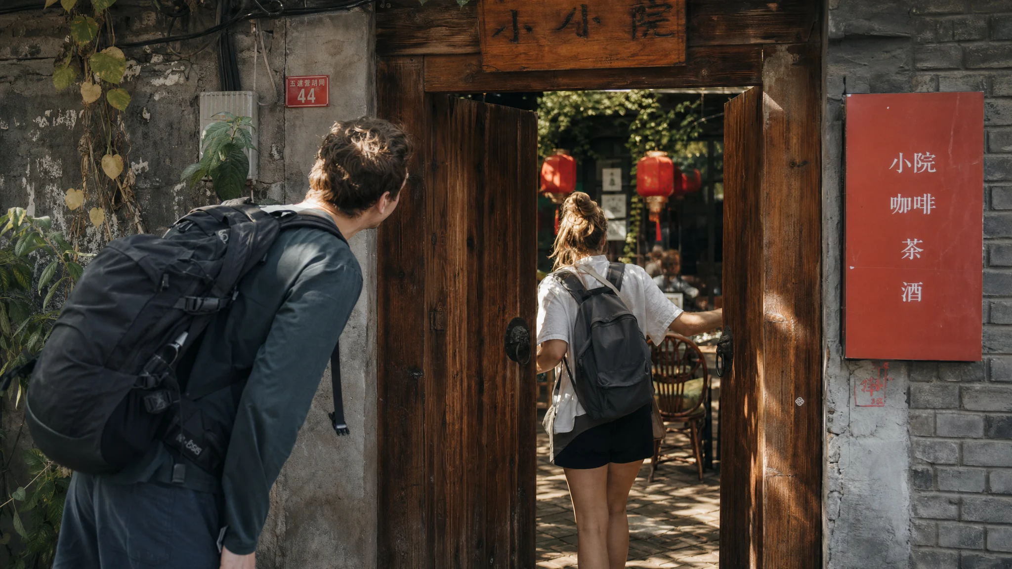 Travelers entering a quiet courtyard cafe in a Beijing hutong