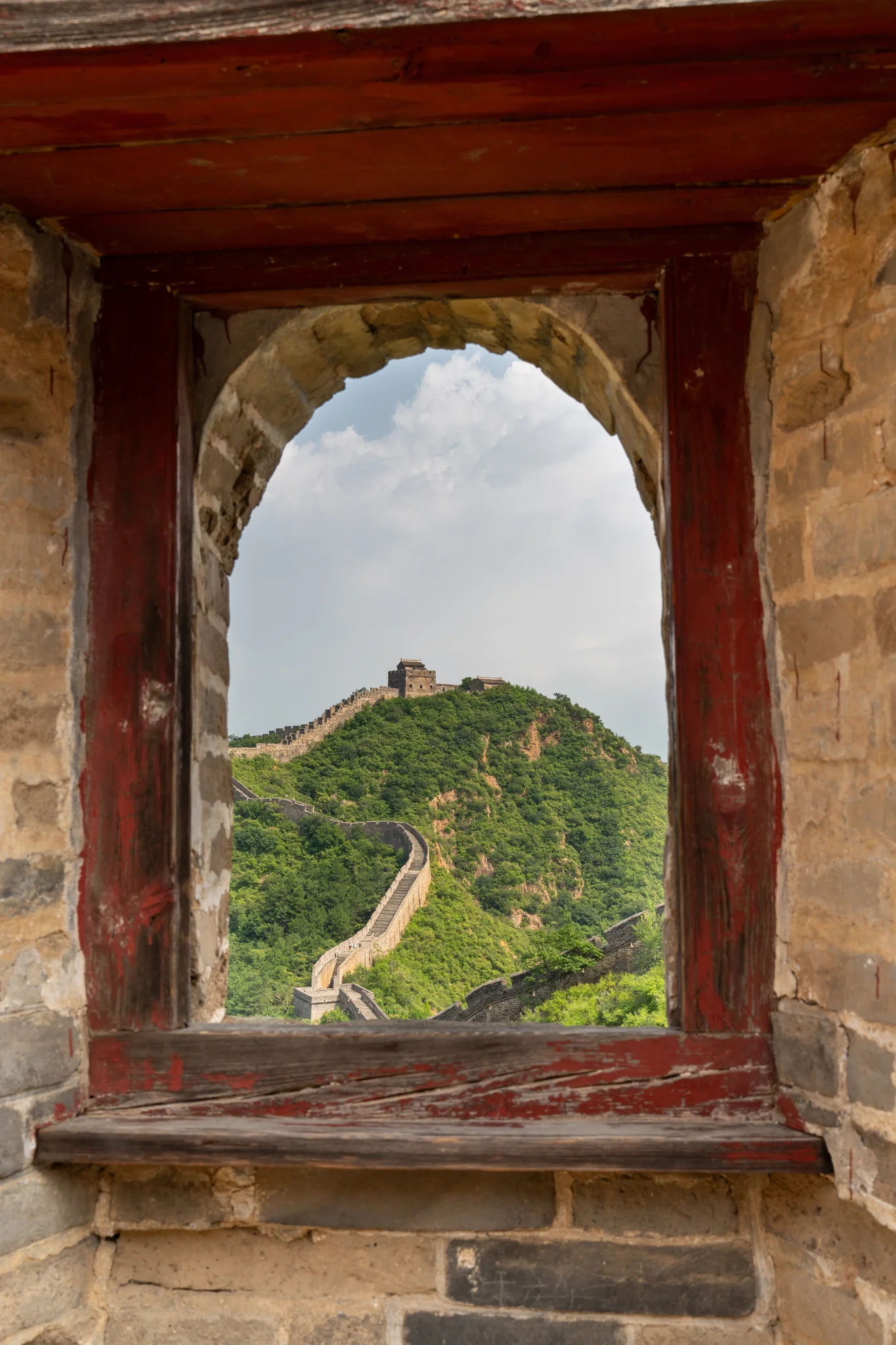The Jinshanling Great Wall framed through a weathered watchtower window