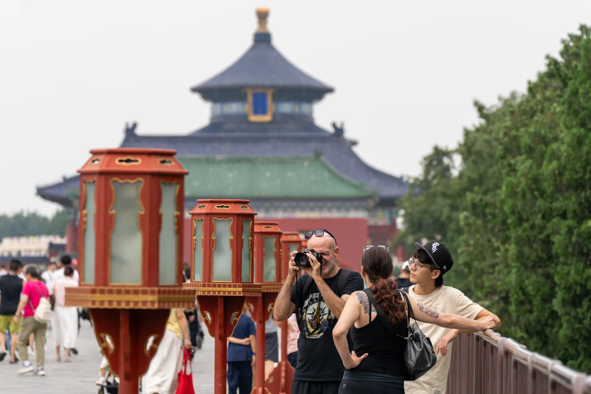 A visitor photographing the Temple of Heaven between ceremonial lanterns