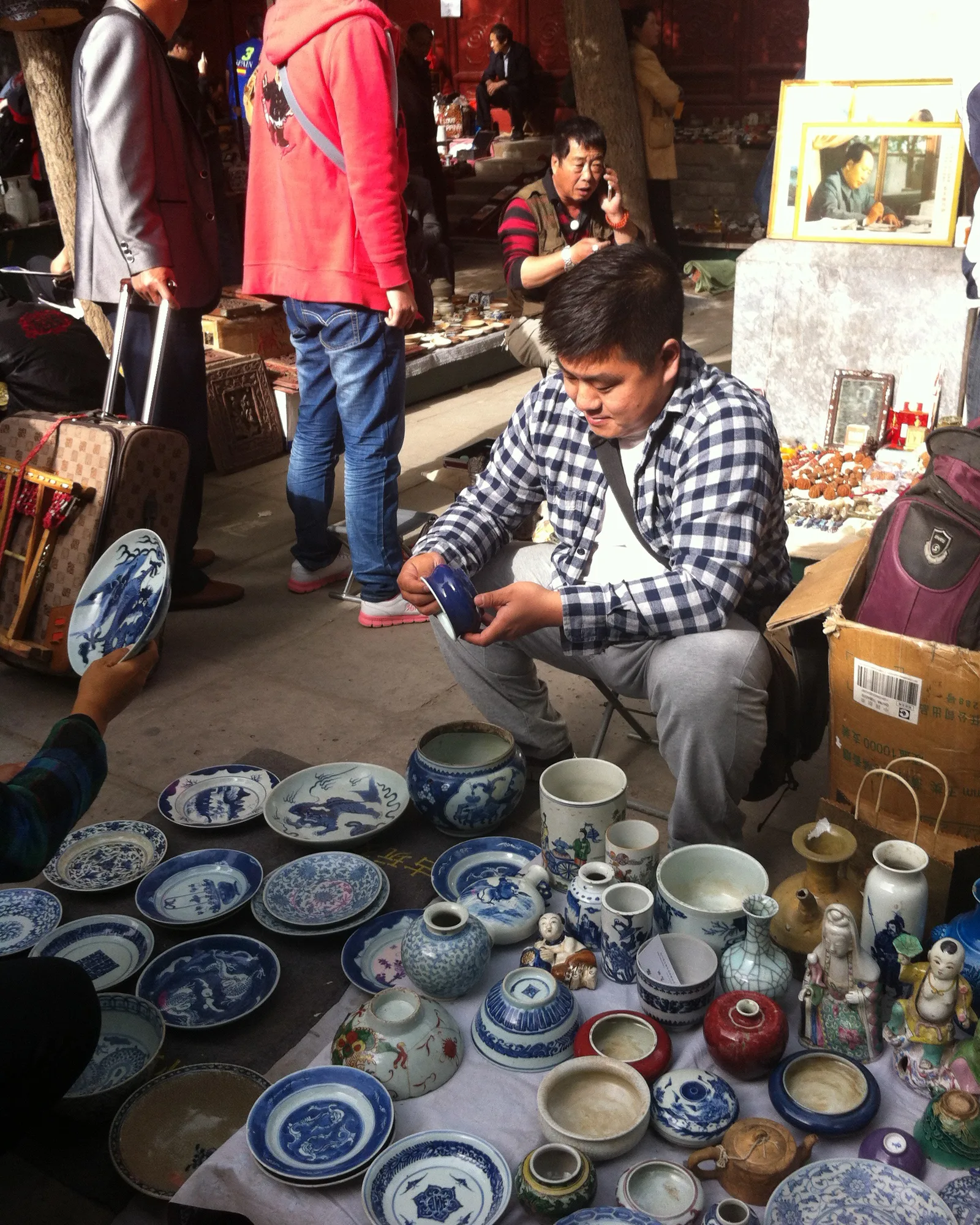 Wang Peng examining ceramics at an antiques market