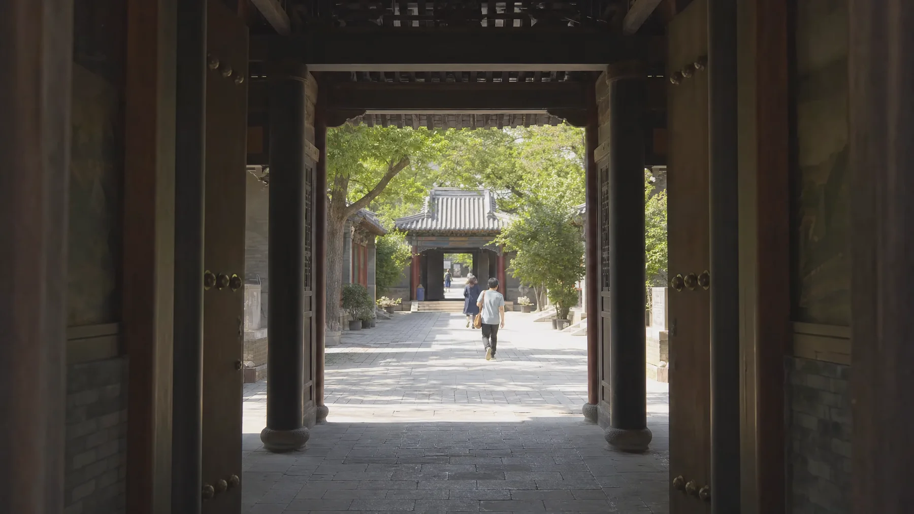 A sequence of shaded gates opening into a Beijing courtyard